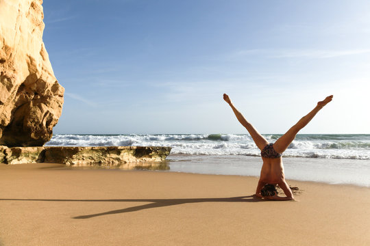 Frau macht Yoga Kopfstand Spagat am Strand, Meer