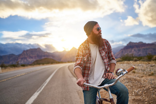 Man On Side Of Road Riding Bike At Sunset In Nevada