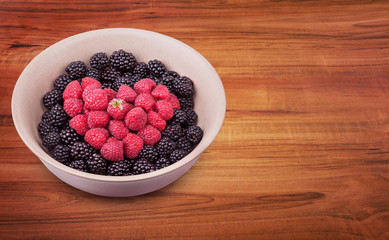 Ceramic plate with heart shaped berries on the left of the wooden table with clipping path. Top side view. Top side view.