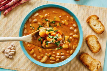 Bean soup in blue dish and wooden spoon takes bean soup