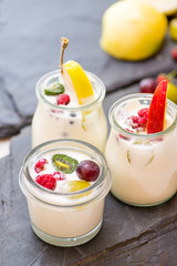 jars with yogurt and colorful fruits on a white background