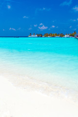 Fototapeta na wymiar Seascape with rolling waves on a sandy beach and boats, Maldives