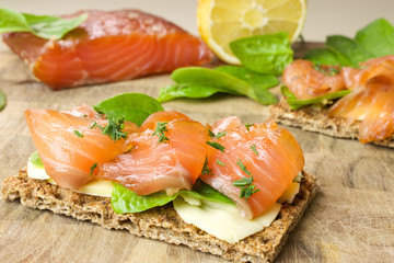 Sandwich with salted marinated salmon on wooden background