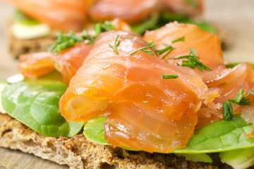 Sandwich with salted marinated salmon on wooden background