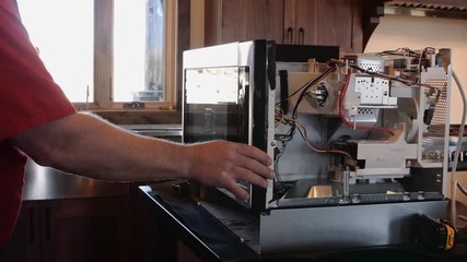 An appliance technician looks at a microwave circuit boards