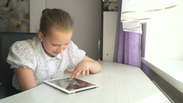 Cute little girl uses a digital tablet computer