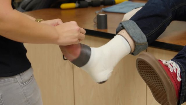 A nurse tapes a boys sprained ankle