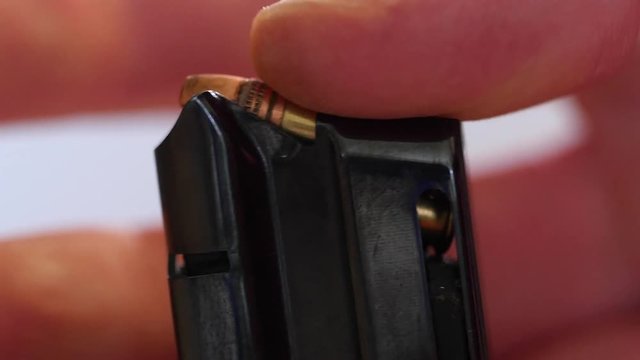 Closeup man loads bullets into magazine