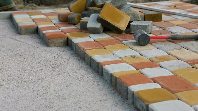 Laying Paving Slabs by mosaic close-up. Road Paving, construction. Repairing sidewalk. Worker laying stone paving slab. Laying colored tiles in a city park. Hand fixed tessellated sidewalk tile