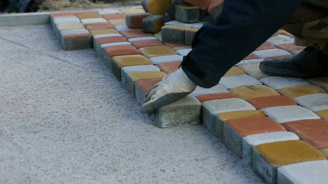 Laying Paving Slabs by mosaic close-up. Road Paving, construction. Repairing sidewalk. Worker laying stone paving slab. Laying colored tiles in a city park . Hand fixed tessellated sidewalk tile