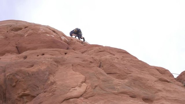 Man climbing redrock in Moab Southern Utah