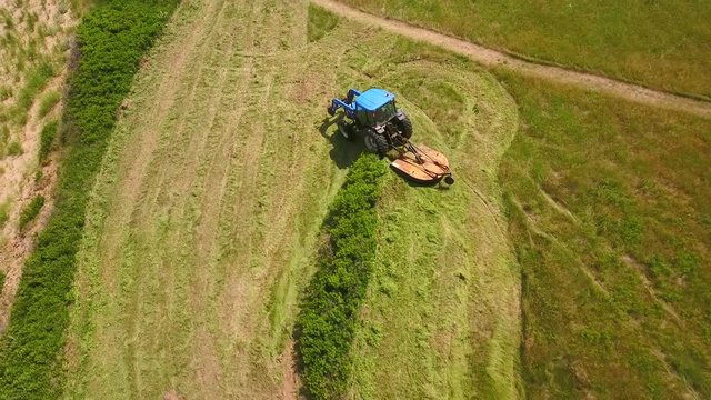 Aerial shot a farmer cuts grass on a field by ocean cove