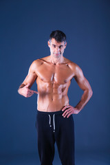 Strong athletic man standing on black background