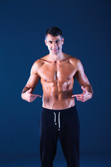 Fototapeta premium Strong athletic man standing on black background