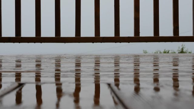 Raindrops falling onto a wood deck in storm