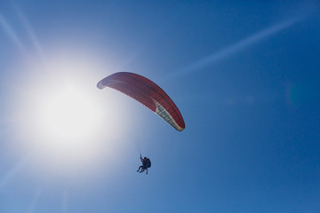Paraglaiding in the blue sky/ Paraglaiding in the blue sky at sun disk background.