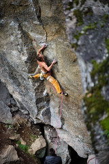 Young man climbing a rock with belay. Extreme rock climbing. Outdoor activity. 