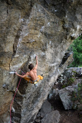 Outdoor sport. Rock climber ascending a challenging cliff. Extreme sport climbing. 