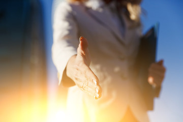 Business woman holding folder and giving handshake outdoor. Hand closeup