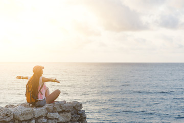 Fototapeta na wymiar Happy hikers girl sitting on rock and looking at sea
