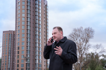 Man talking on the phone on the background of the new building