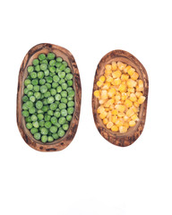 Frozen organic peas and corn in olive wood bowl isolated on white background