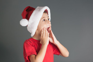 Portrait of surprised little boy with Santa hat