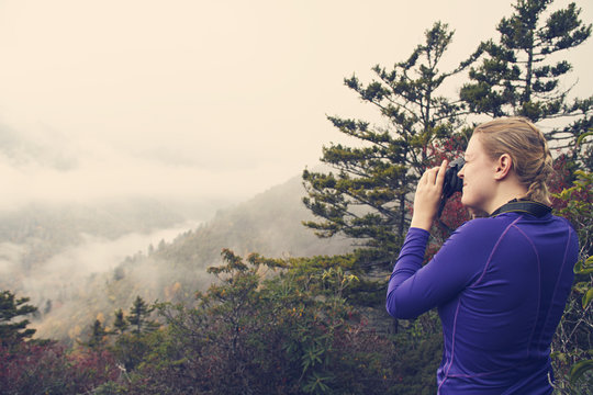 Woman photographing mountains while on a hike