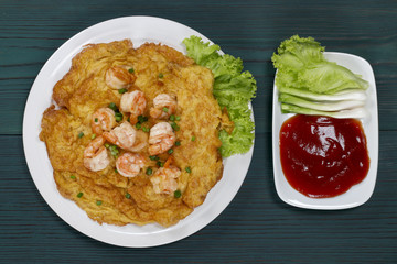 Omelet with shrimp on a wooden table green, thai food
