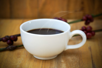 Hot coffee on the wood and raw coffee bean.