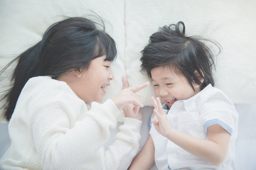 Cute asian children lying on white bed