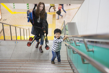 The mother has a stroller and is climbing the stairs of the station