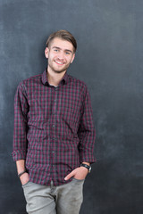 Trendy relaxed young man with a modern haircut standing against