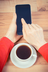 Vintage photo, Hand of woman touching blank screen of mobile phone, cup of coffee