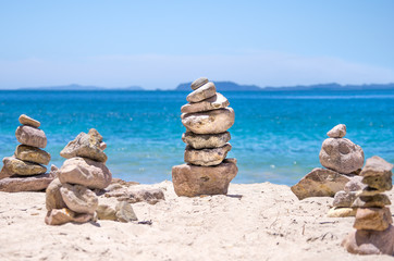 Fototapeta na wymiar Stones stacked on the blue water beach
