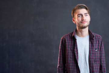 Trendy relaxed young man with a modern haircut standing against