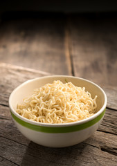 Instant noodles in a bowl on wood board.