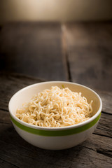 Instant noodles in a bowl on wood board.