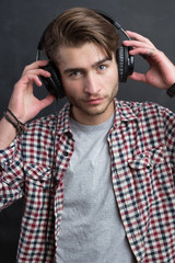 Portrait of confident young DJ with stylish haircut and headphon