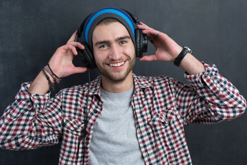 Portrait of confident young DJ with stylish haircut and headphon