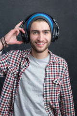 Carefree music lover. Joyful young man in headphones smiling aga