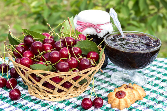 Basket of cherries, cherry jam with biscuit, cherry jam jar on background of  cherry tree
