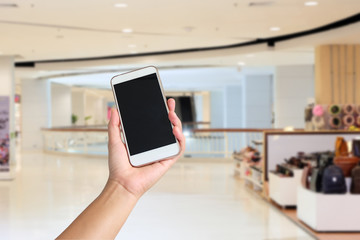 Woman hand holding the white smartphone on blurred backg