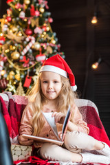 Little cute girl with book near christmas tree