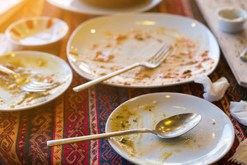 Empty dirty plates with spoon and forks on the table with a bright tablecloth, sunny