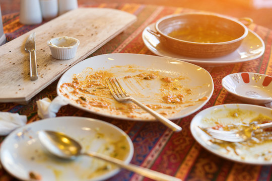 Empty dirty plates with spoon and forks on the table with a bright tablecloth, sunny