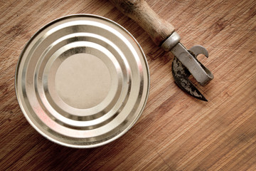tin can and can opener on wooden background