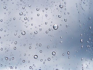 Water drops on the glass window with the reflection of cloud in every raindrops