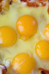 Raw fried eggs with tomatoes and onion, background