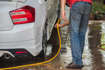 Man washing his car and pulverizing water all over with a dynamic look suggesting car wash services on a premium auto vehicle in business car care